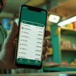 Retailer managing business finances using the Udhaar Book digital khata app on a smartphone.